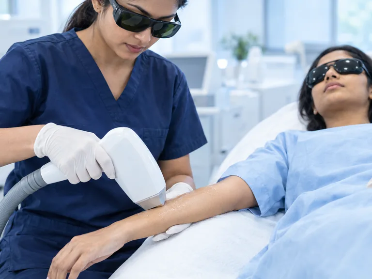 AI-generated image: a clinician in safety glasses treating a patient's forearm with a handheld laser, the patient wearing protective goggles