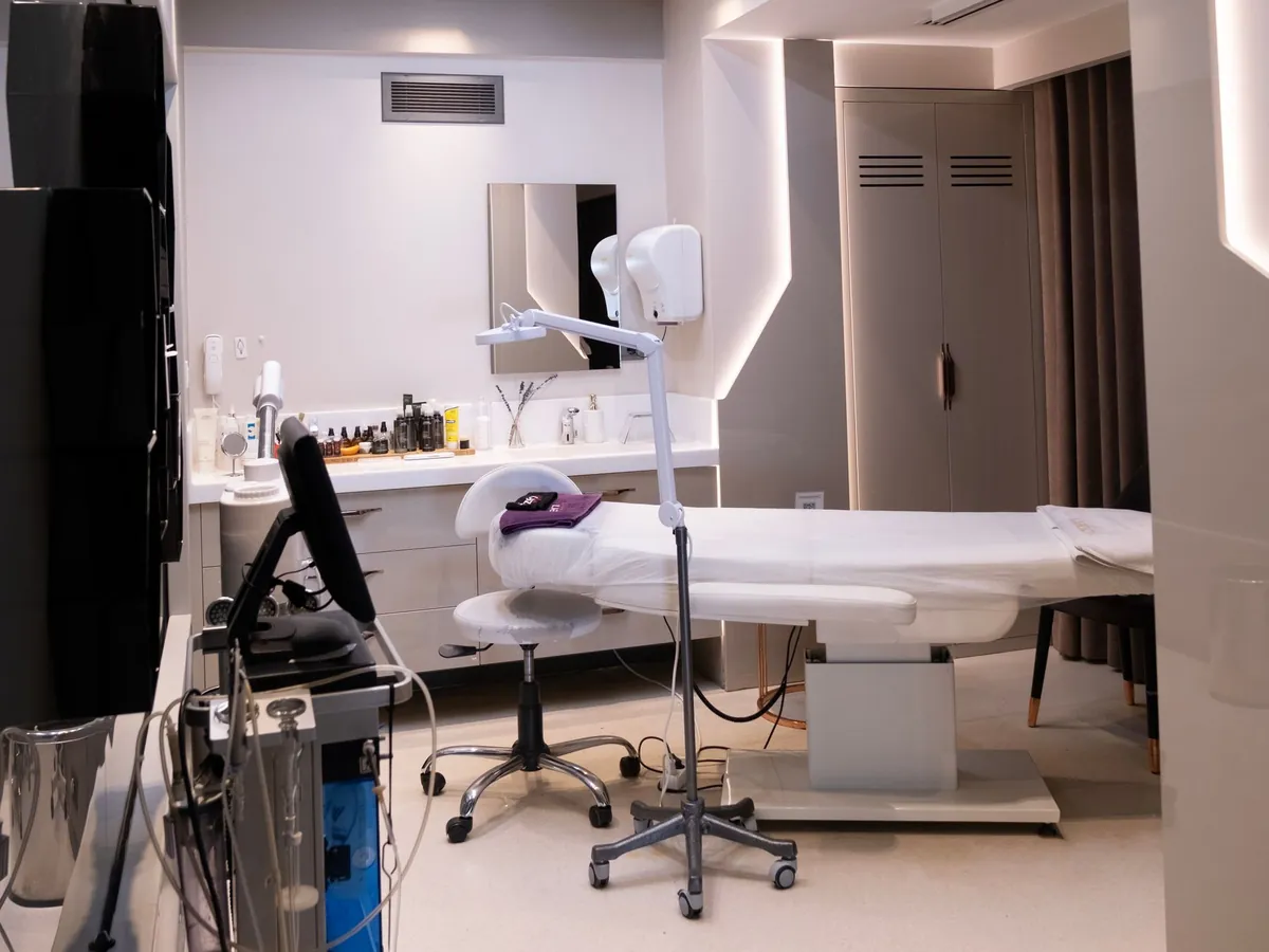 Representative image of a clinic treatment room with a treatment couch, lamp and equipment